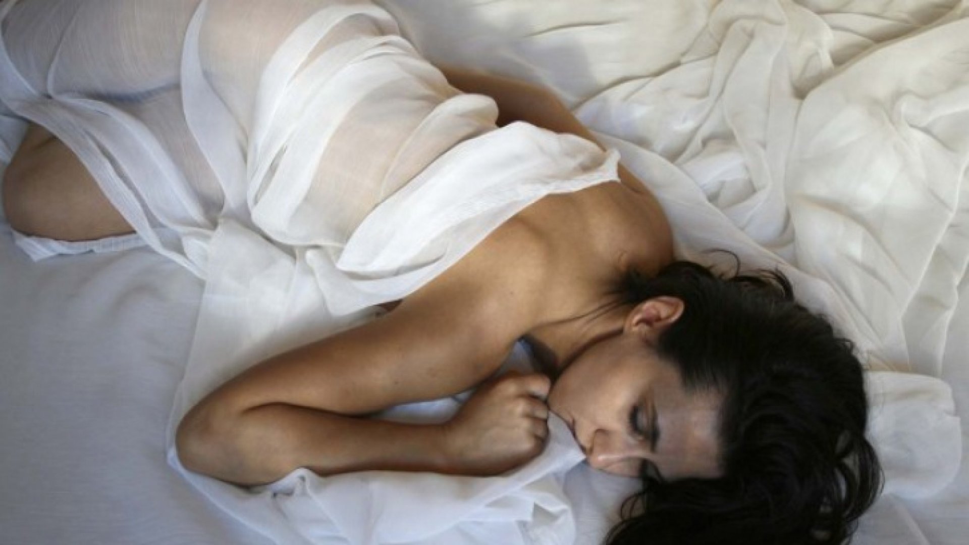 Выпившая женщина лежит голышом на кровати