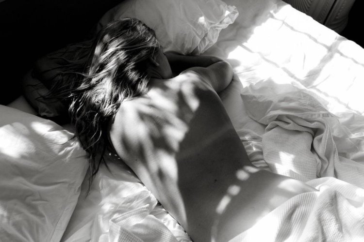 Девушка спит на кровати спиной