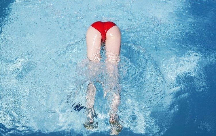 Брюнетка в бассейне в одежде