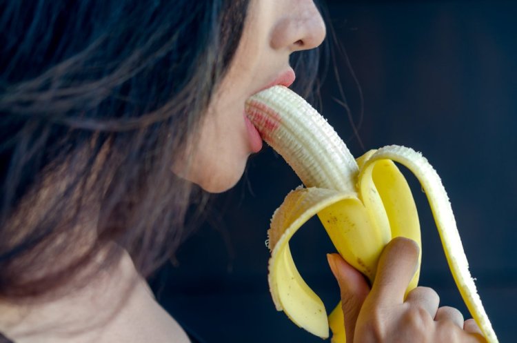 Молодая девушка ест банан