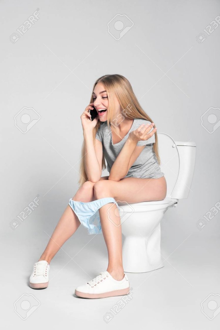 Красивая девушка сидит на унитазе
